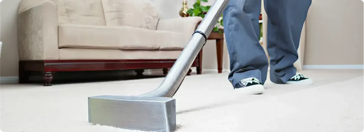 Carpet cleaning technician using a hot-water extraction wand on a light-colored carpet in a living room, Phoenix, AZ.