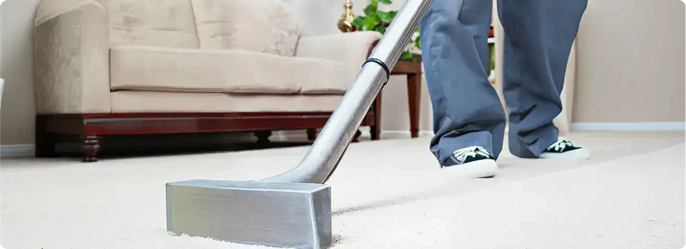Carpet cleaning technician using a hot-water extraction wand on a light-colored carpet in a living room, Phoenix, AZ.