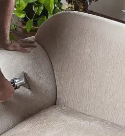 Professional upholstery cleaner deep-cleaning a fabric sofa with a handheld extraction tool and hose Phoenix, AZ.